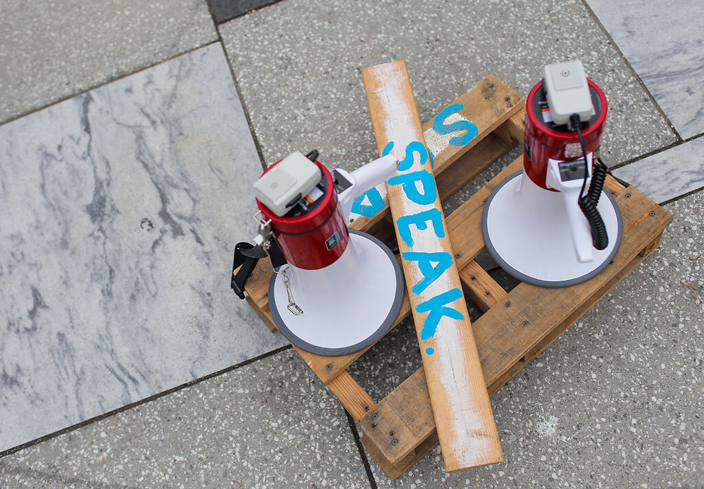 Megaphones and a pallet to stand on are placed on the sidewalk for people to speak
